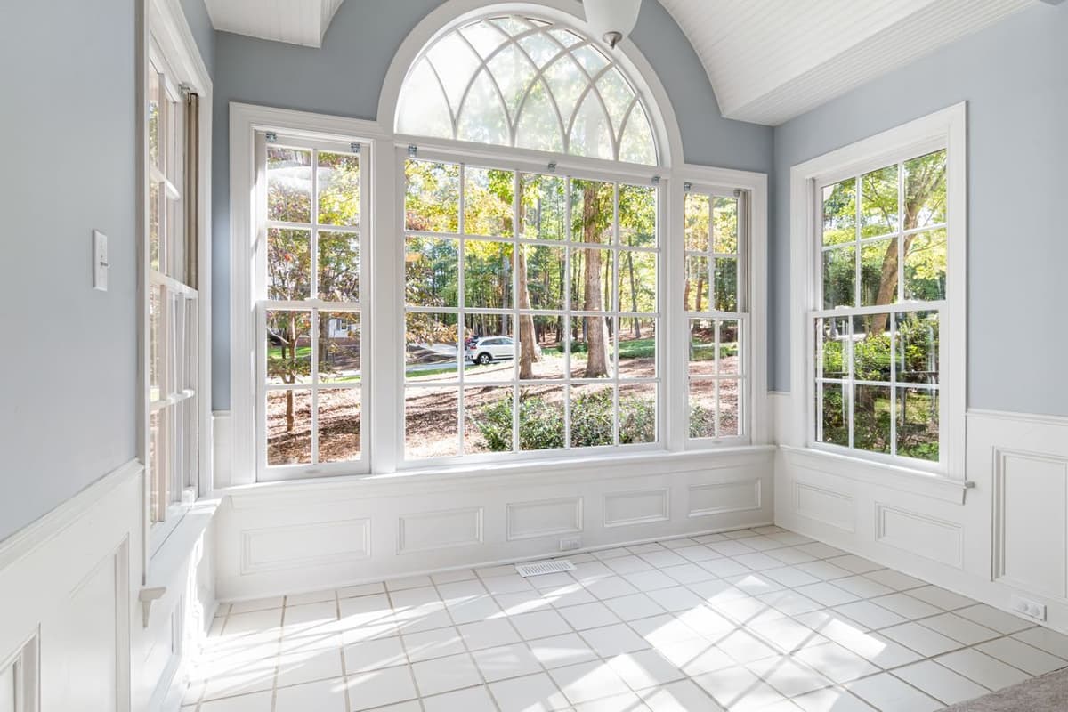 Sunroom with tall white-framed windows beneath an arched window