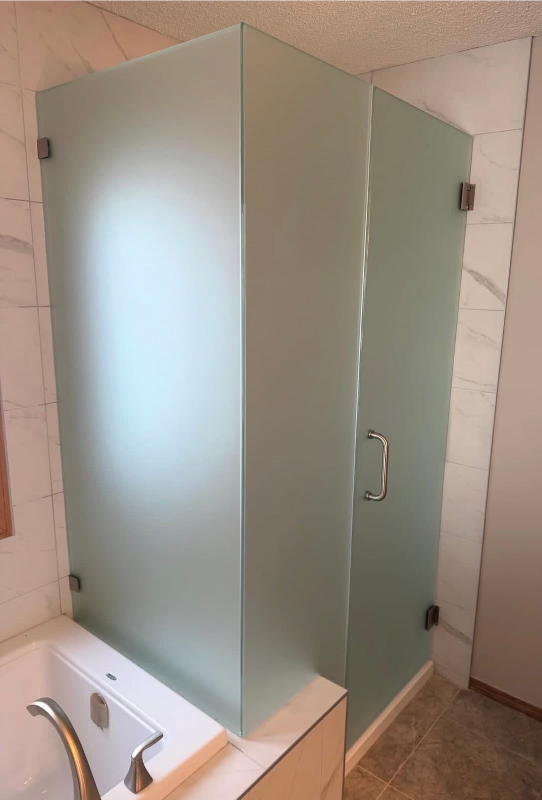 Frosted glass shower panels and door above a tub deck