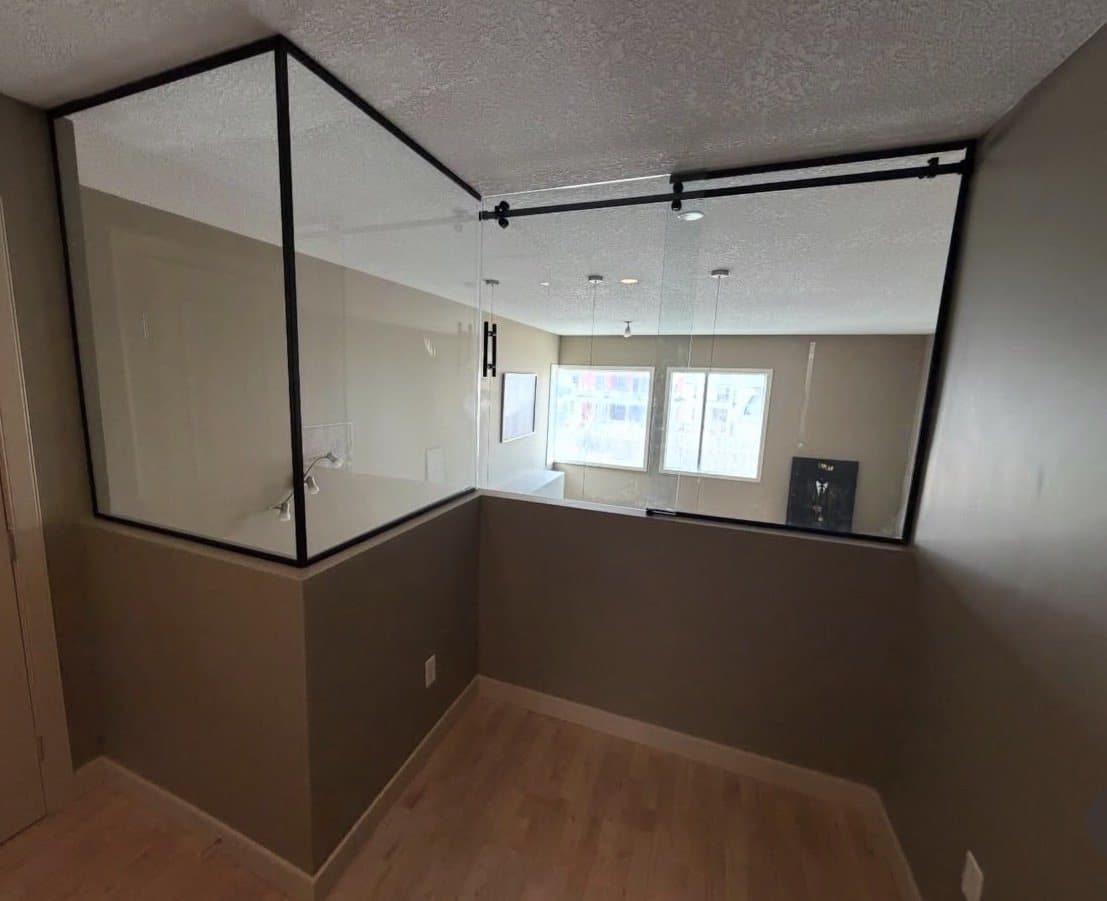 Black-framed glass partition across a room above a half wall