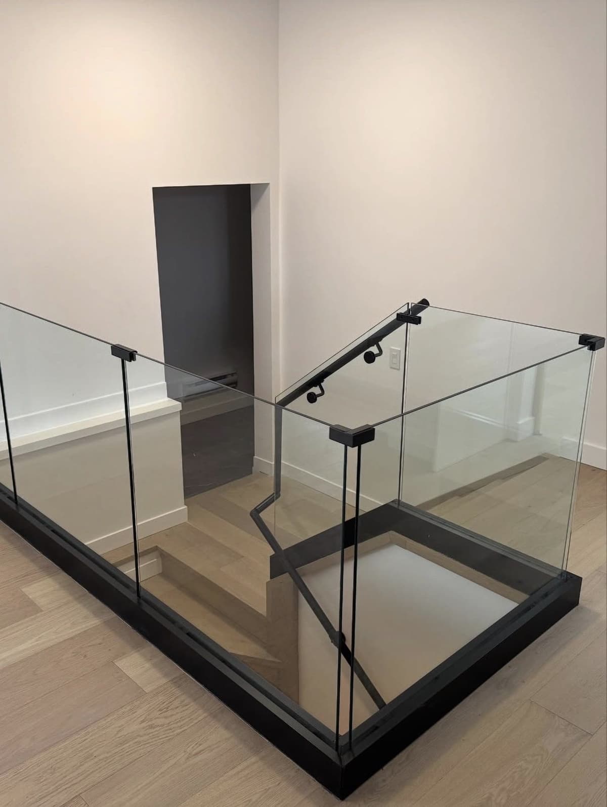 Glass landing railing set into a black base channel around a stairwell